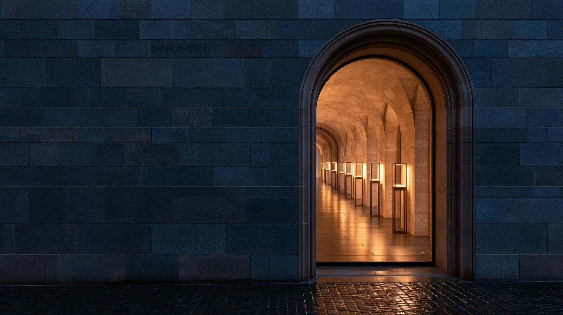 The arched entrance of a covered passage at dusk, lit glass display cases inside