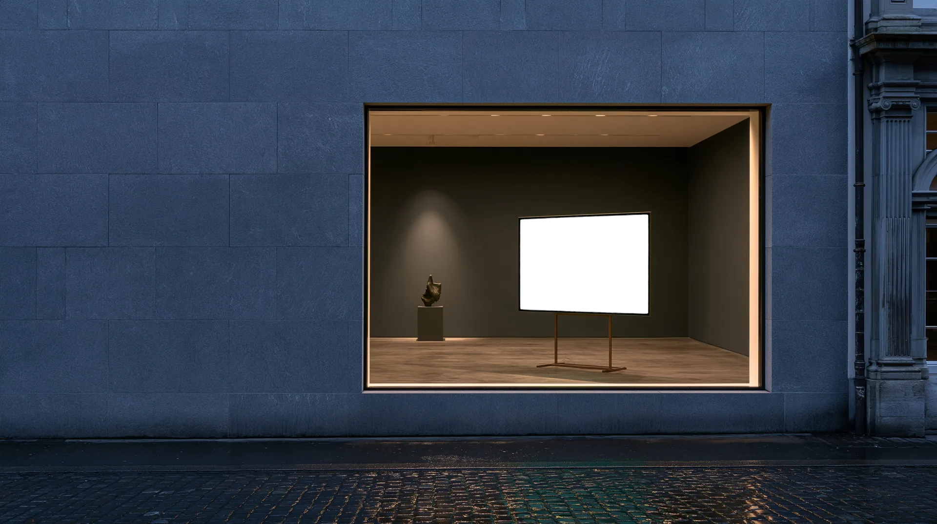 A charcoal gallery window with a small bronze sculpture on a plinth and a screen showing the Volume museum website